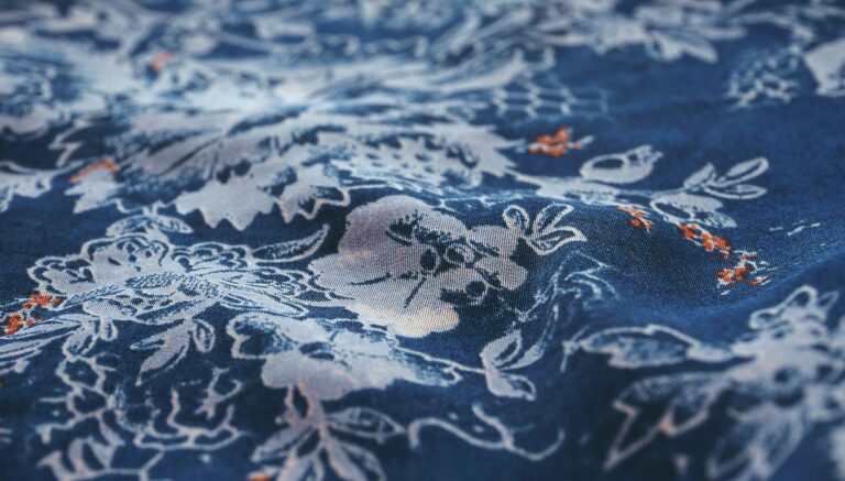 Close-up view of a blue fabric showcasing intricate white floral patterns, perfect for textile enthusiasts.
