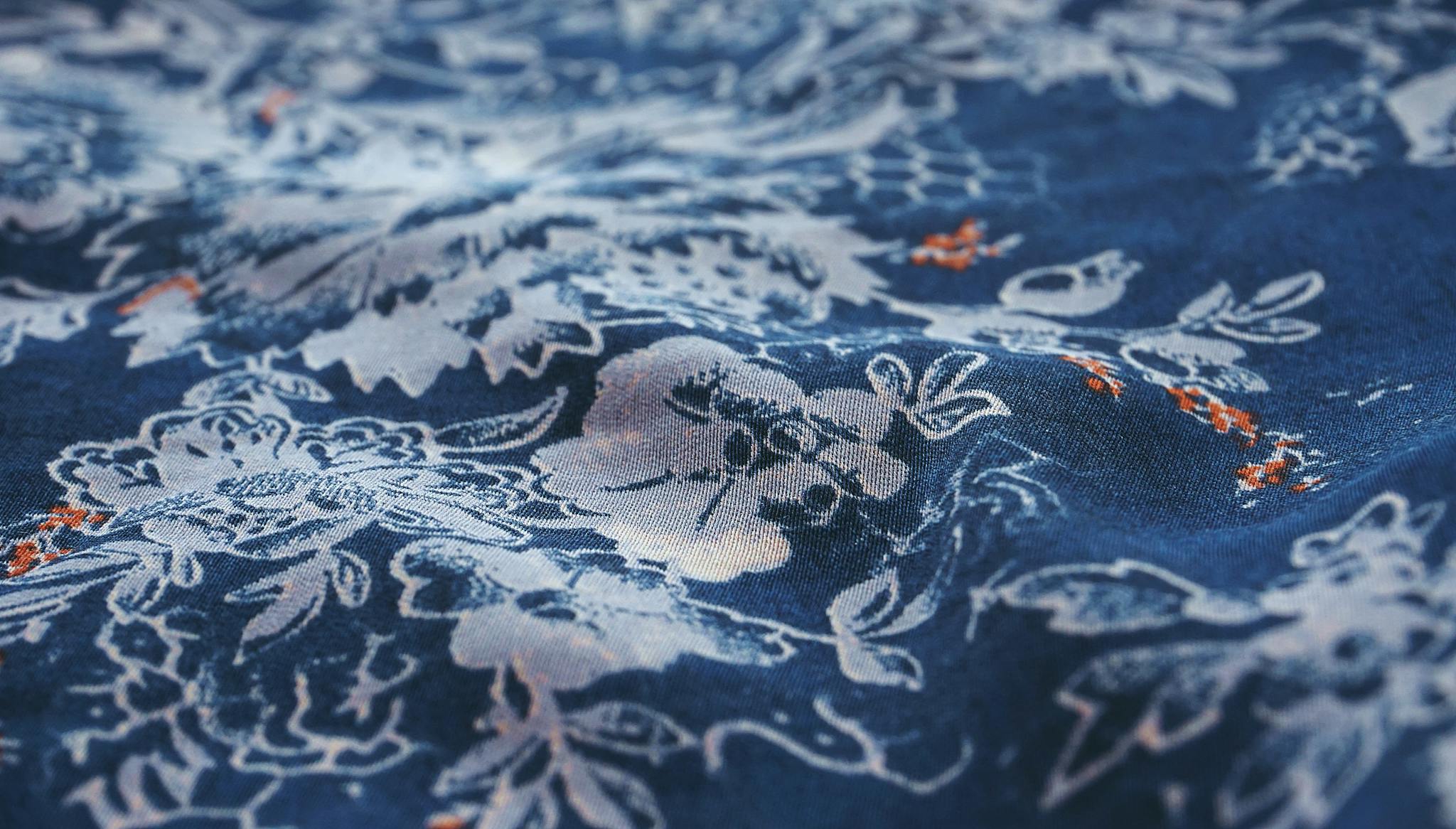 Close-up view of a blue fabric showcasing intricate white floral patterns, perfect for textile enthusiasts.