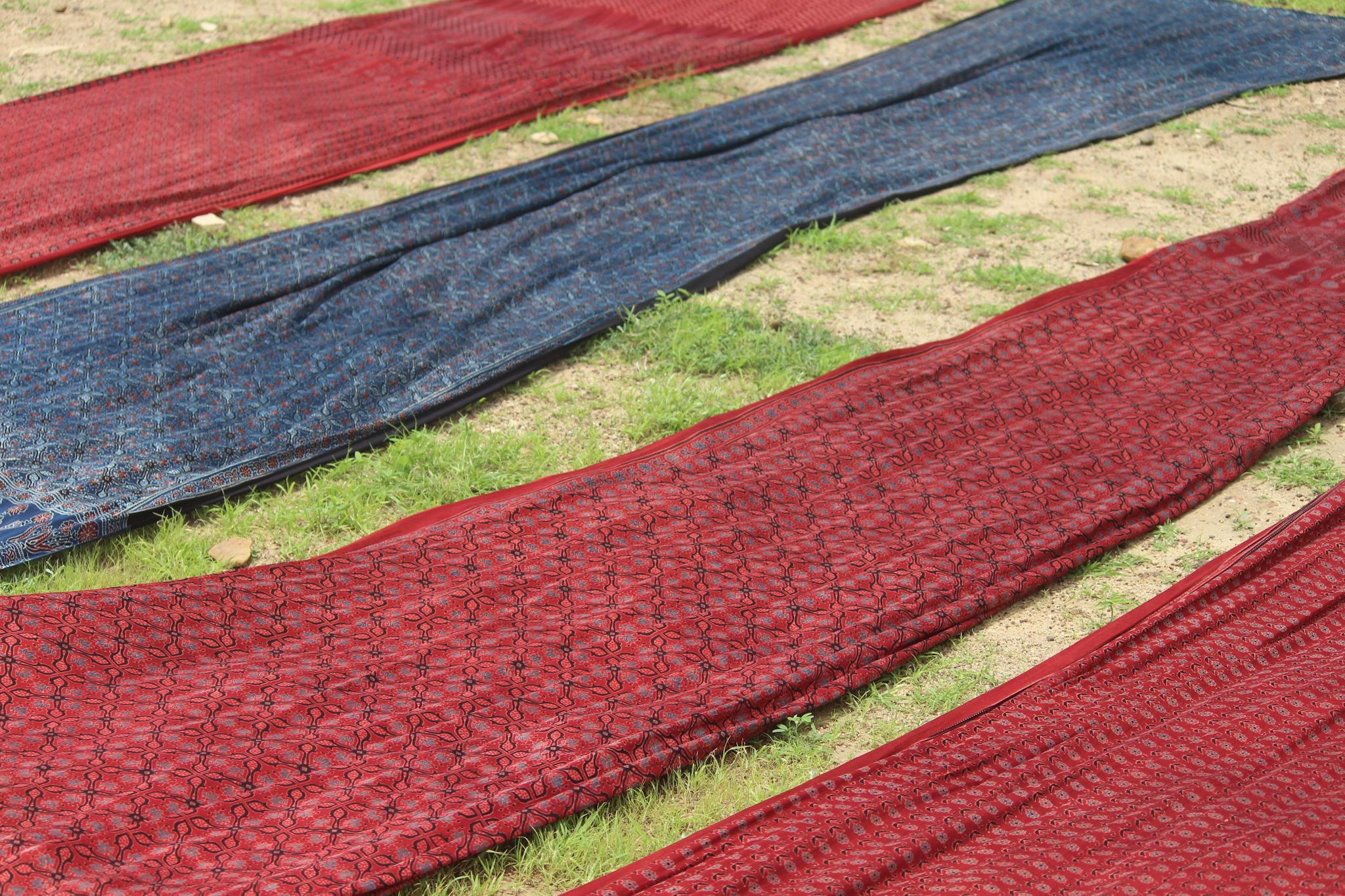 Colorful Ajrakh fabric drying outdoors in Ajrakhpur, India, showcasing traditional textile craftsmanship.