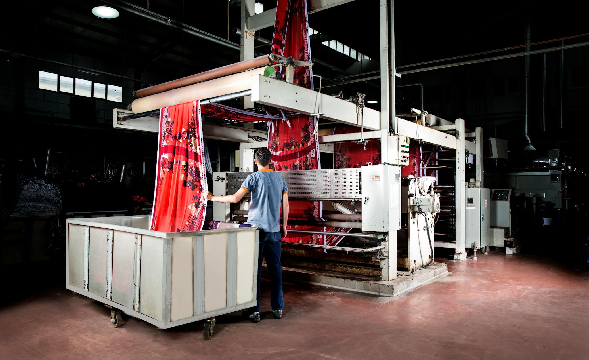 Worker operates machinery in a textile factory, overseeing fabric production.